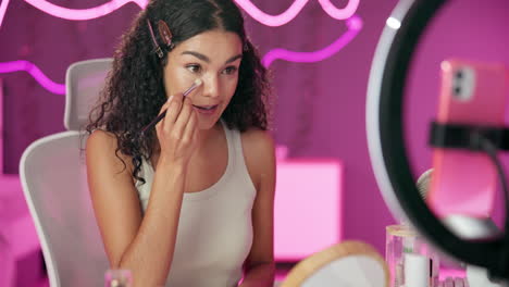 woman applying makeup with ring light