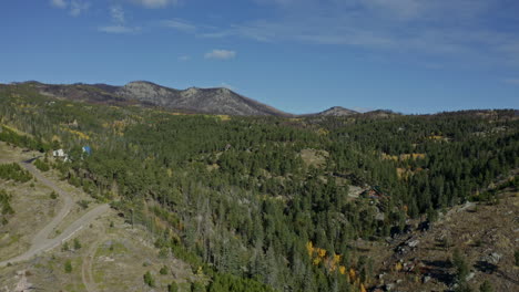 aerial passing over small scenic cabin on side of mountain in fall, 4k