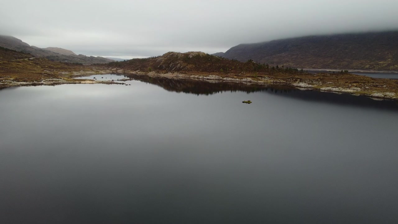 Luftperspektiv, der svæver over den rolige, spejllignende overflade af Loch Cluanie, og fanger det stemningsfulde landskab i det skotske højland.