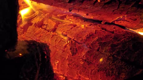 close-up of red hot embers and cracked burning logs radiating intense heat. bright orange flames and glowing textures fill the frame.