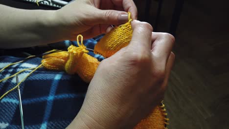 women's hands knit woolen jacket with knitting needles. top view, close-up of hands and knitting.