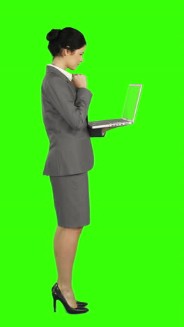 mujer de negocios de pie y usando una computadora portátil