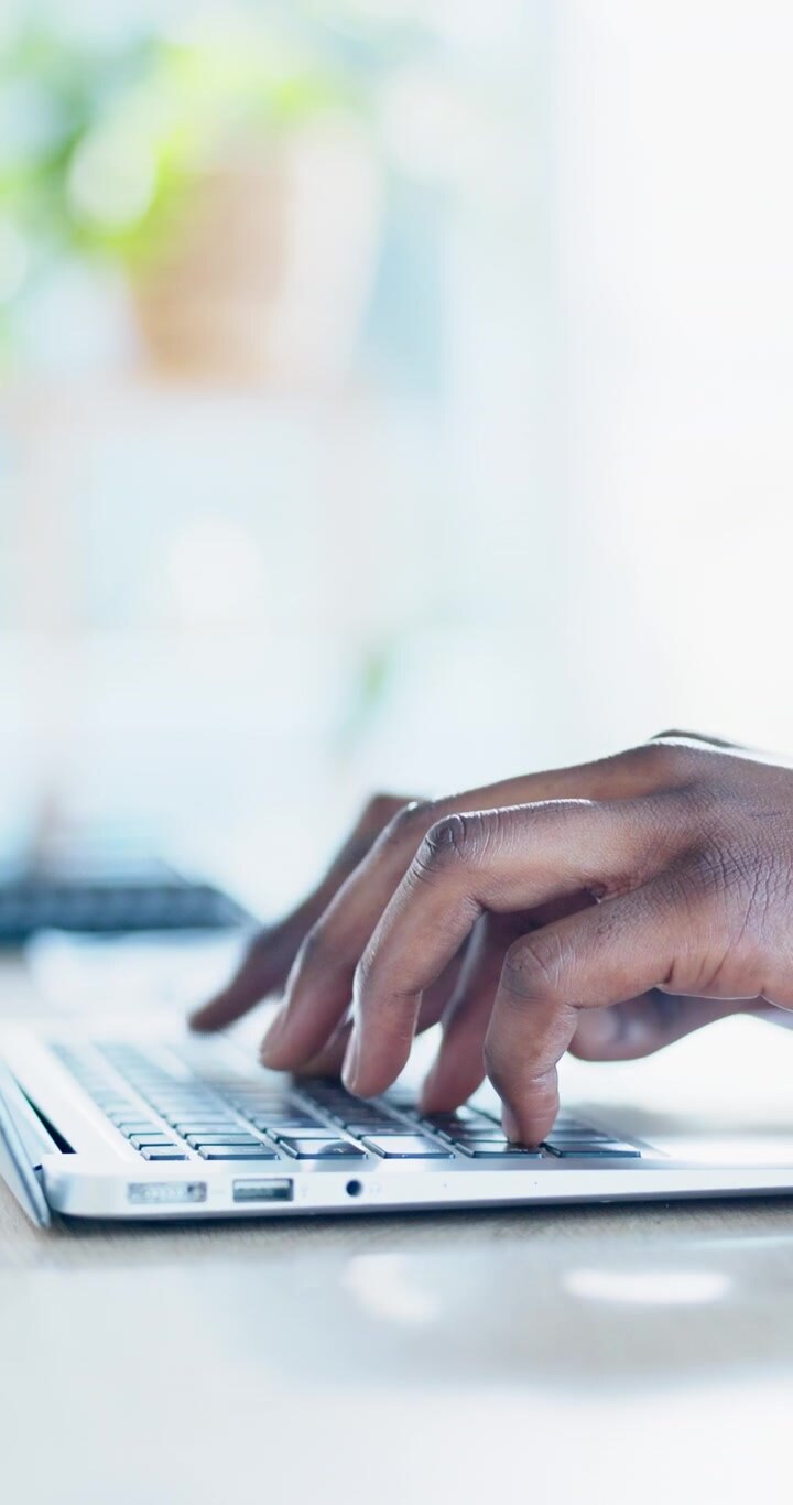 Close-up of Person Typing on Laptop Keyboard in Bright Office