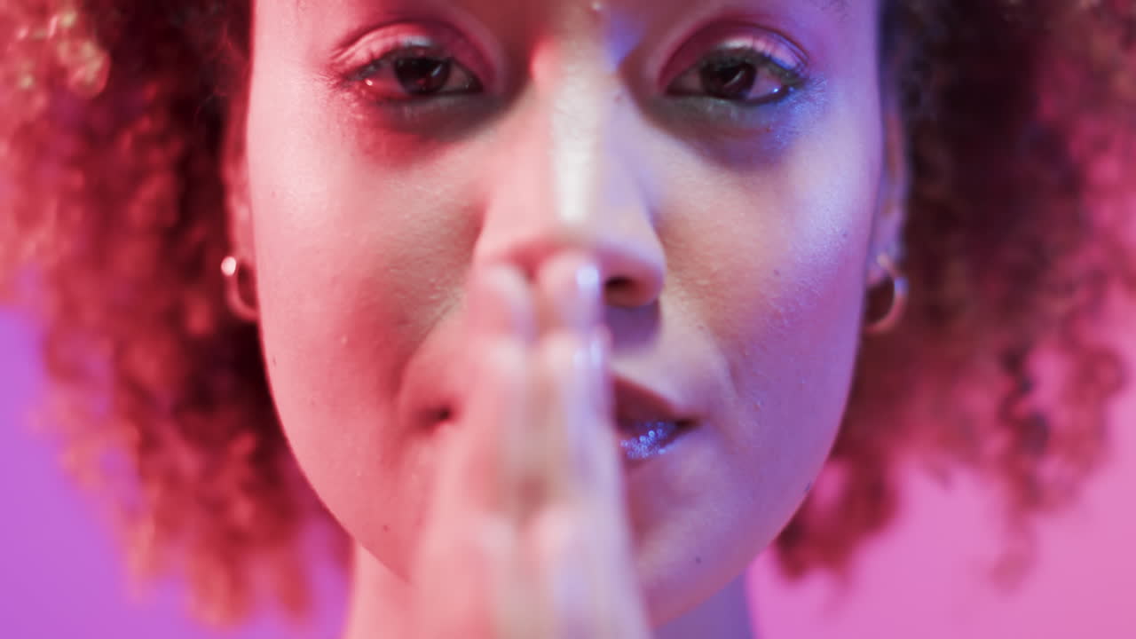 mujer biracial con cabello oscuro en luz azul y rosa, cámara lenta