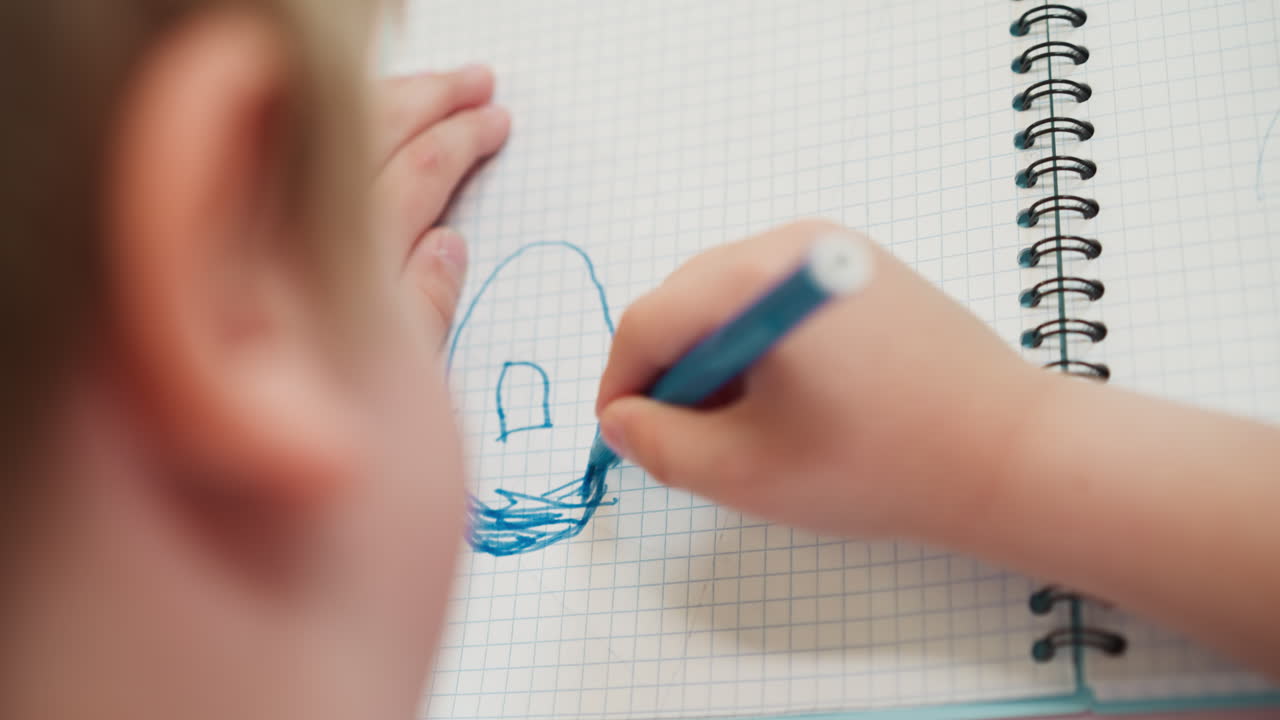 Menino pequeno colorindo um donut com caneta hidrográfica azul em uma página de caderno