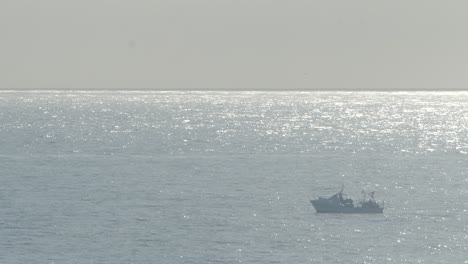 a fishing boat drifting on the ocean waves as a fisherman works on deck