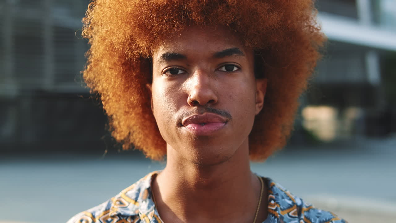 Ritratto ravvicinato di giovane uomo con capelli afro che guarda in camera
