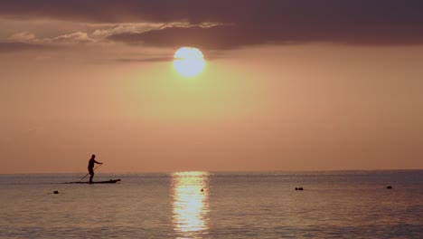 silueta de un remador solitario durante la puesta de sol dorada cerca de la costa de chipre