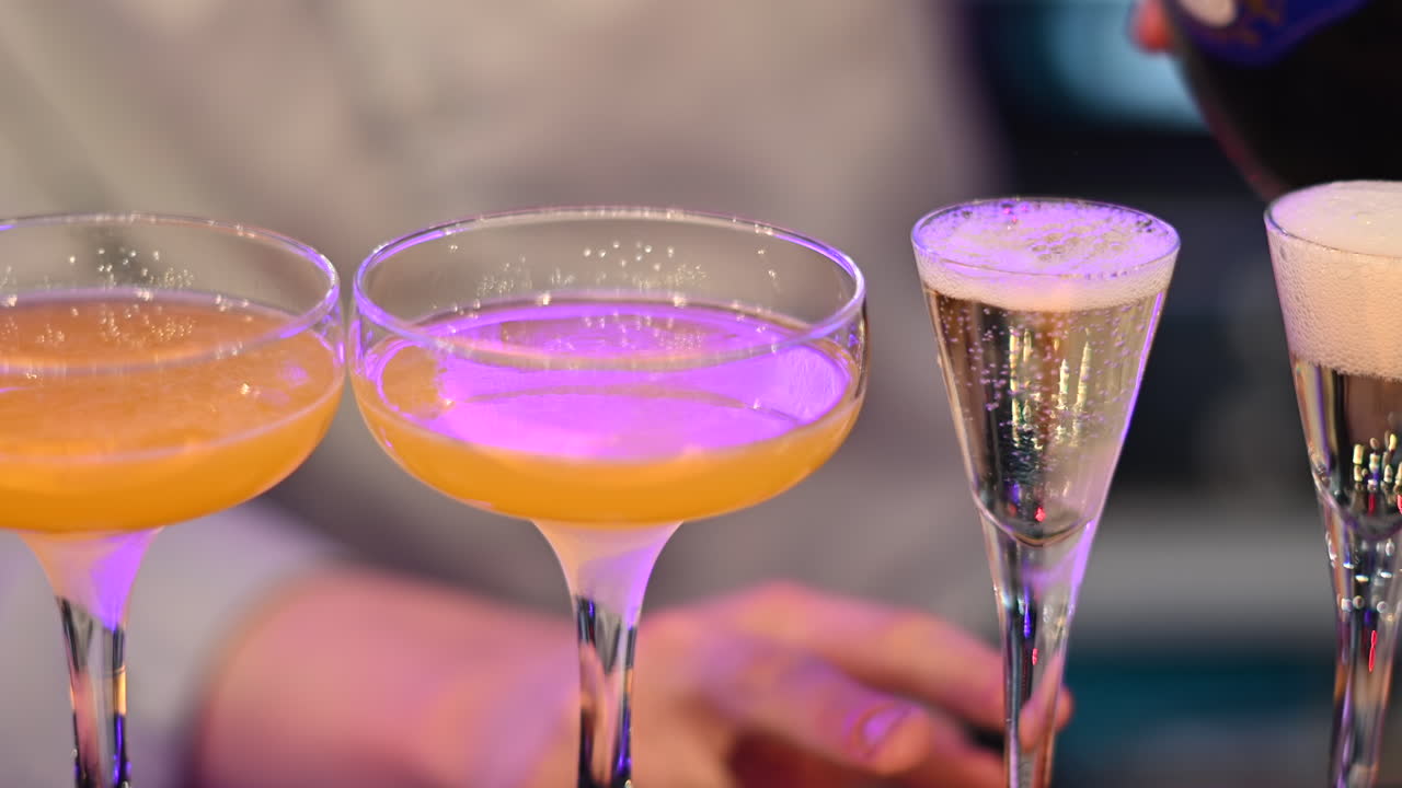 Barman servindo champanhe em taças perto de coquetéis amarelos em um bar