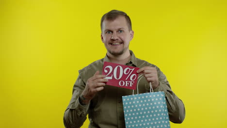 happy man showing 20 percent off inscription from shopping bag, smiling, rejoicing discounts