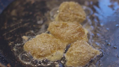 chicken fillet pieces rolled in breadcrumbs placed in a hot frying pan and baked at home