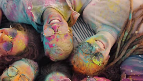 close-up portrait of human faces covered with powder paint smiling lying on blanket during holi festival