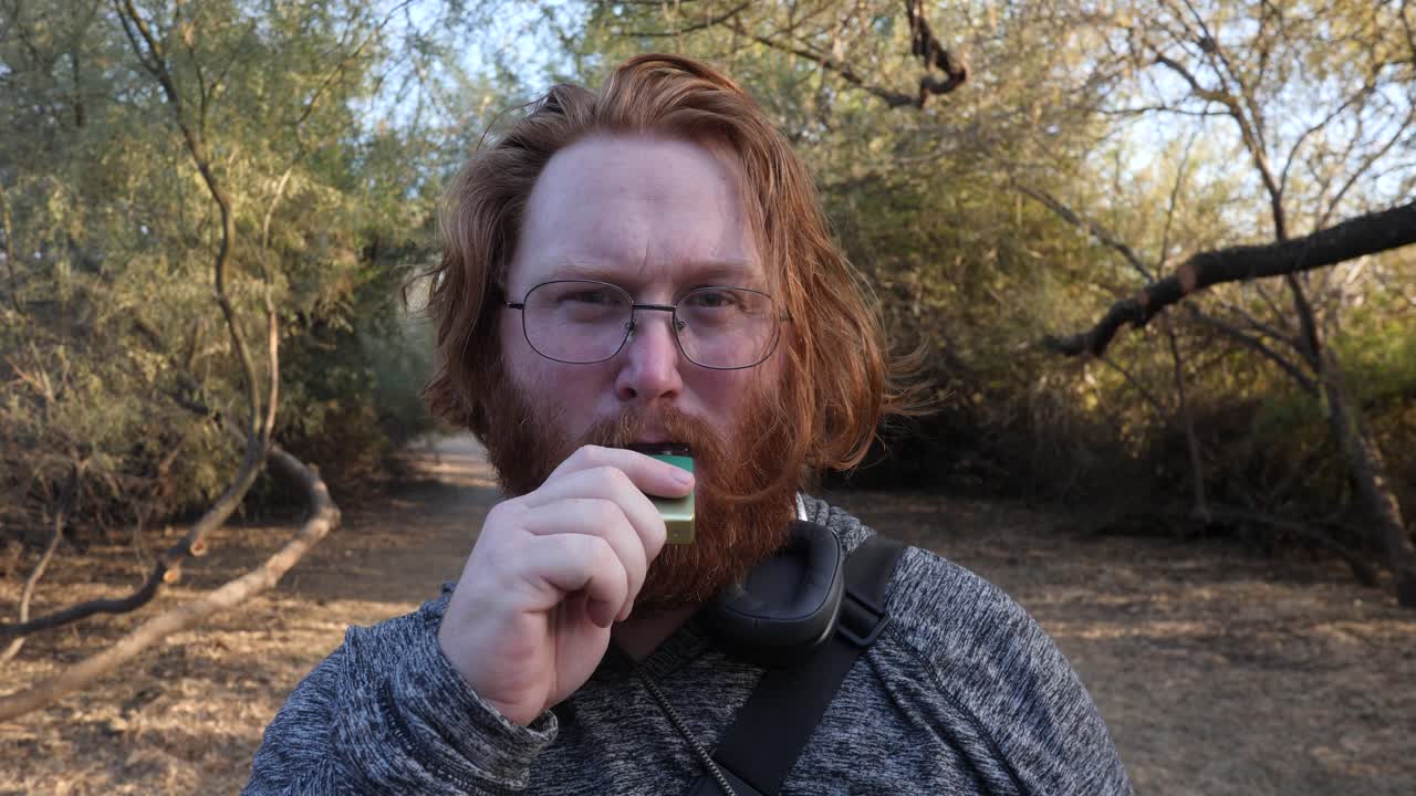 Red hair man close up vaping while facing camera
