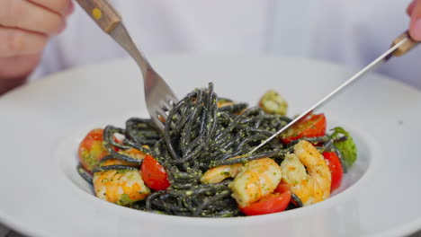 eating black pasta with shrimp and pesto