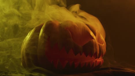 video of halloween carved pumpkin with smoke and orange light on black background