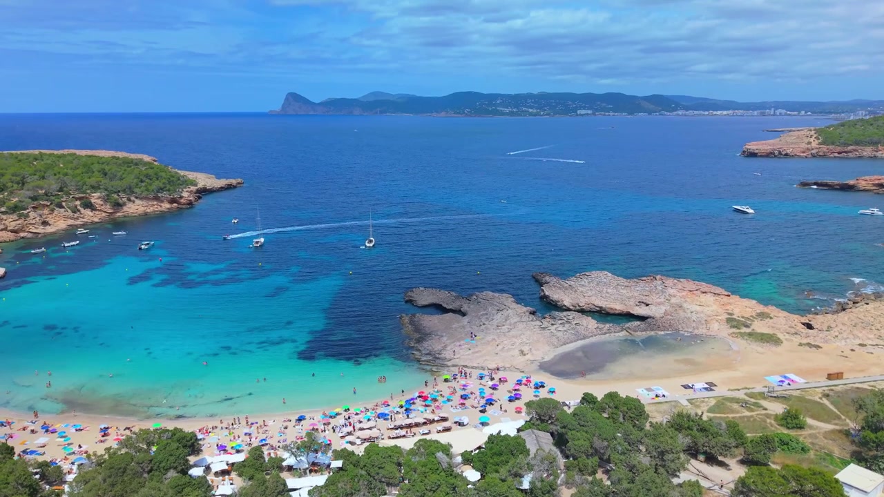 Ripresa aerea panoramica che cattura la costa e l'oceano limpido di Cala Bassa in una giornata di sole