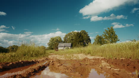 countryside dirt road with puddle and house