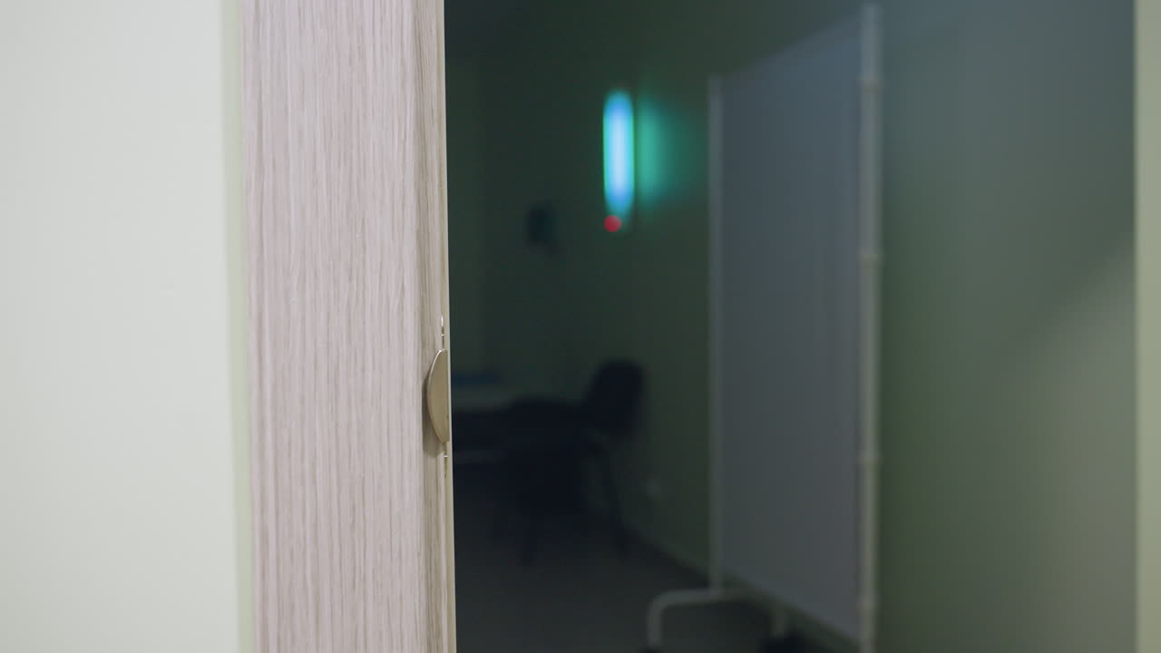 Elegant woman opens wooden door using chrome handle stepping into softly lit room with chair visible in background then gently shuts door behind her symbolizing calm entry privacy peaceful transition