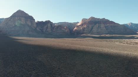 Aerial-drone-shot-of-Red-Rock-Scenic-Highway-with-mountains-in-the-background