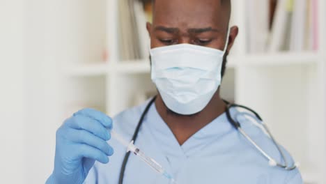 Video-of-african-american-male-doctor-in-face-mask-preparing-vaccine