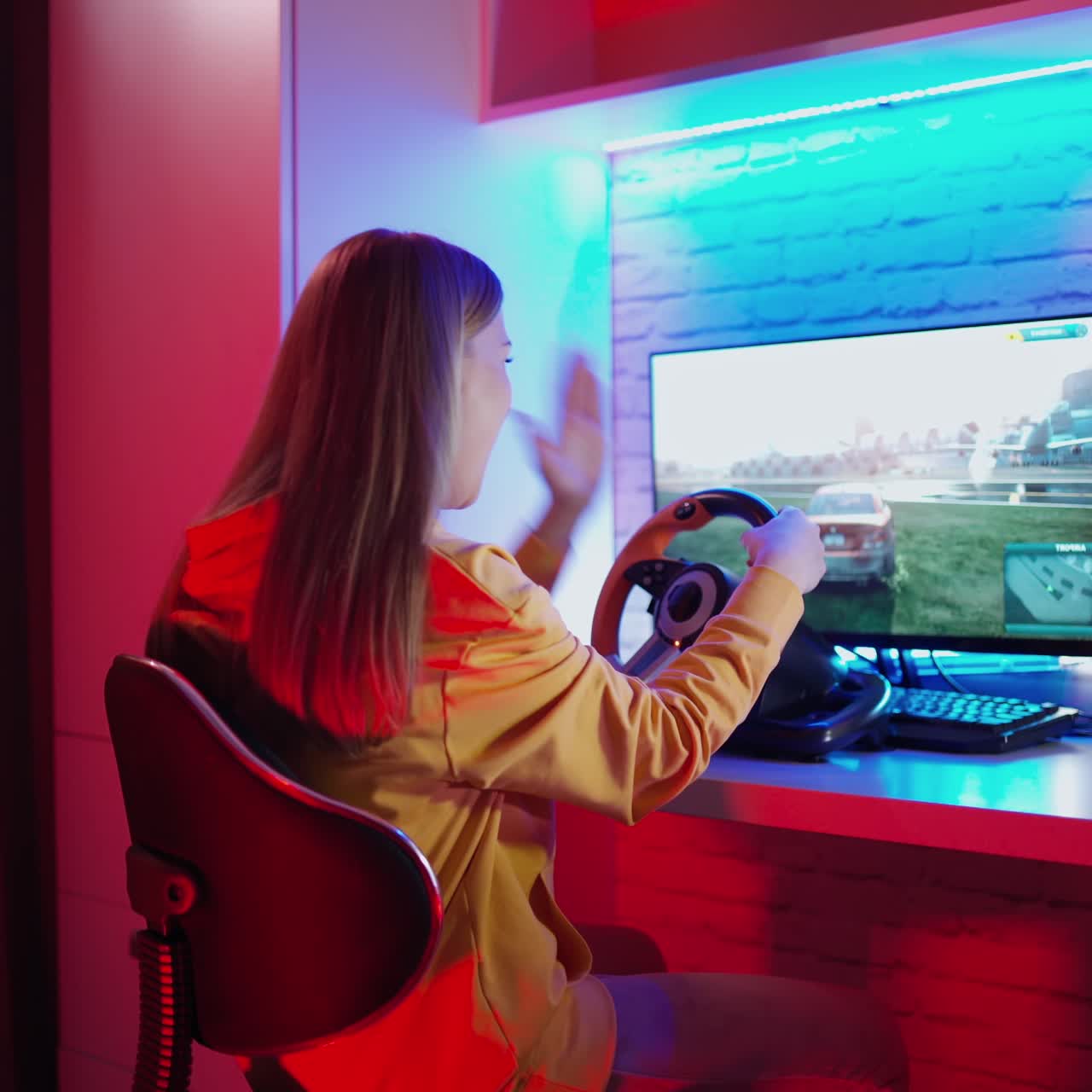 Nervous woman playing a video game. Girl sitting in front of the computer and playing with disappointment. Racing with a steering wheel at home. Gaming at home.
