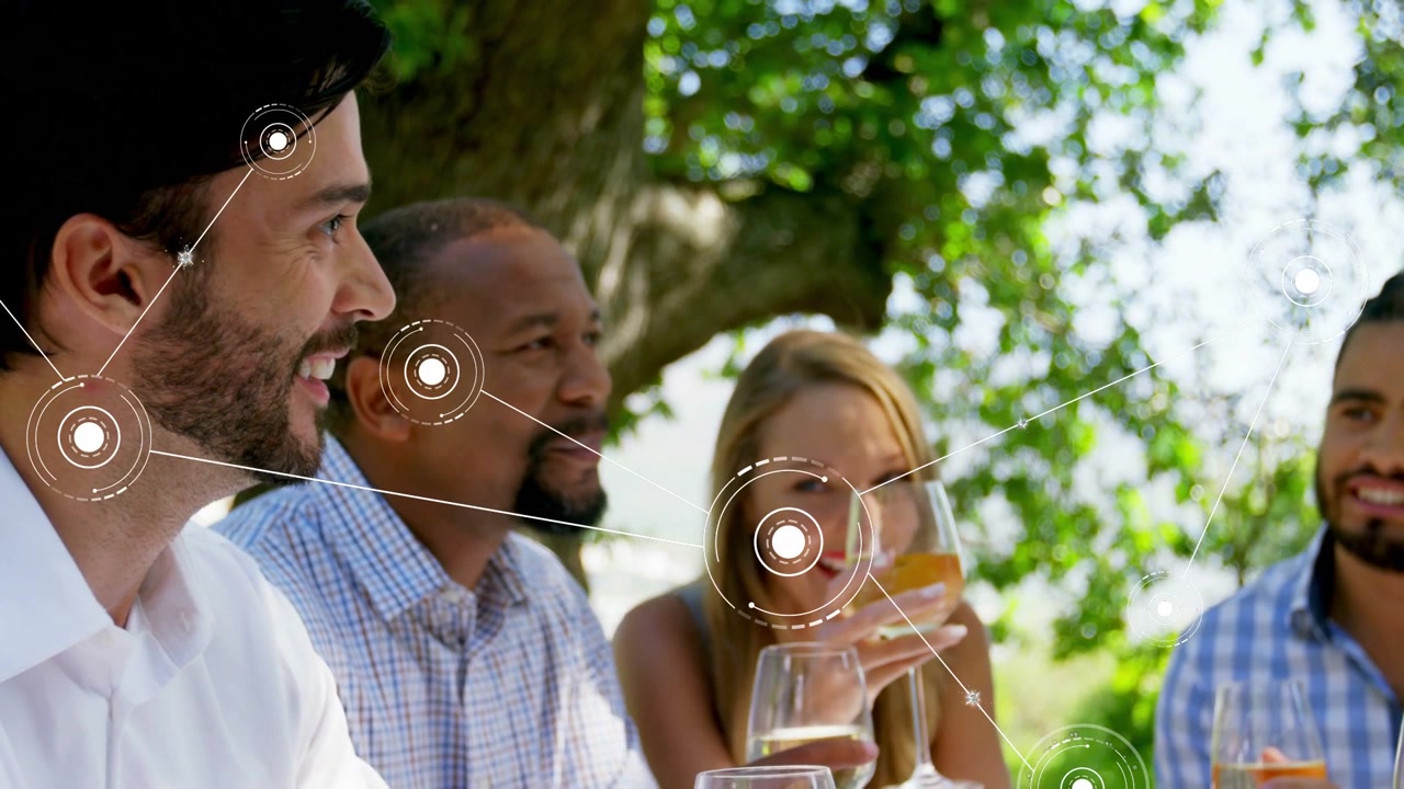 Friends chatting under tree, woman lifting glass starting HUDs linking faces, glasses, tech demo