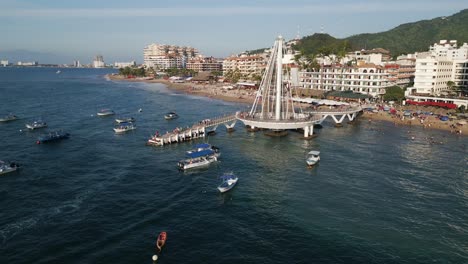 aerial drone zoom out pier boats, puerto vallarta mexican beach town, blue ocean in pacific coastline