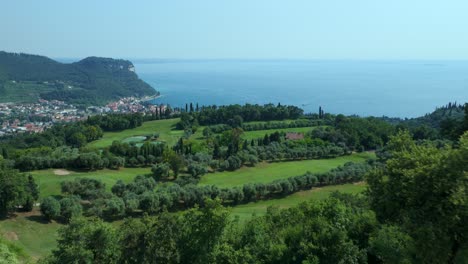 Aerial-Flying-Over-Rooftop-Building-With-Solar-Panels-With-View-Of-Verona-Shore-Of-Lake-Garda-In-Background