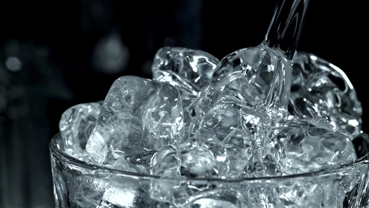 Acqua limpida che si versa su cubetti di ghiaccio in un bicchiere