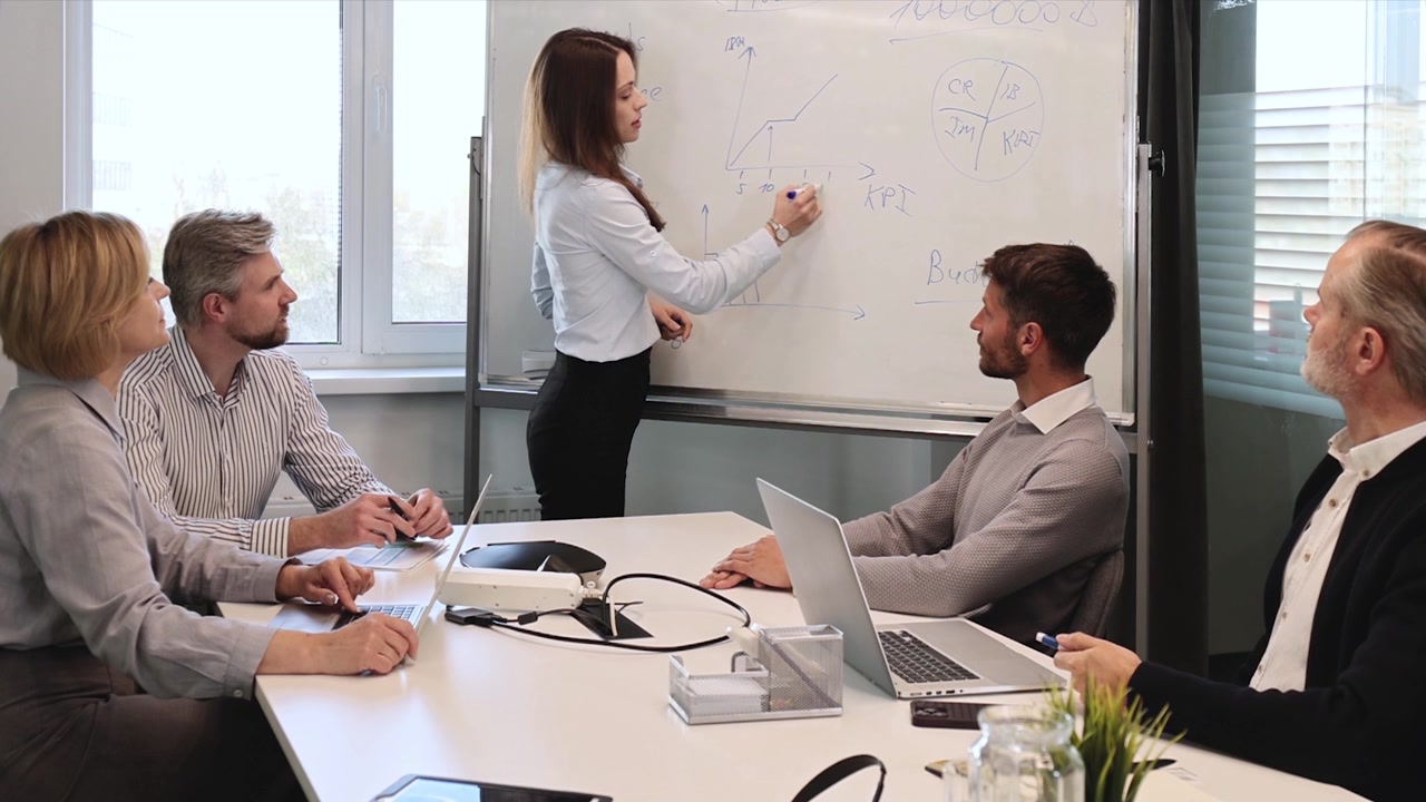 Businesswoman Presenting Data on Whiteboard to Colleagues in Office Meeting