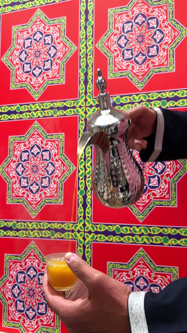 4K close-up of Arabic coffee being served in a traditional dallah pot with a vibrant Islamic-pattern background. Ideal for Ramadan, hospitality, or Middle Eastern culture visuals.