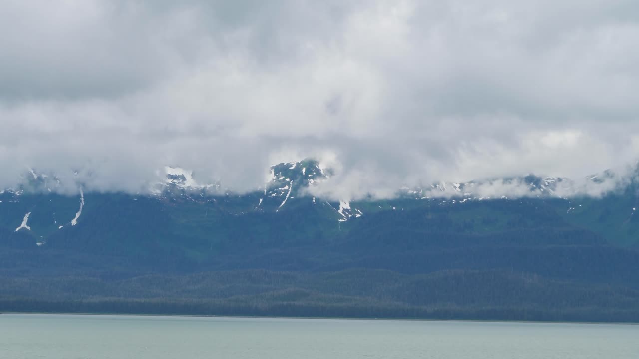 Snow capped mountains covered by clouds. Gastineau Channel, Juneau, Alaska.
