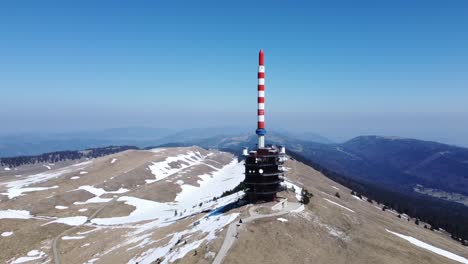 drone flies in a circle around a hill with a red and white television antenna
