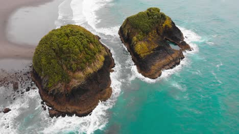 Two-proud-rocks-rise-between-the-black-beach-and-the-ocean-in-New-Plymouth