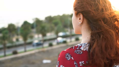 woman with red hair looking at the sunset