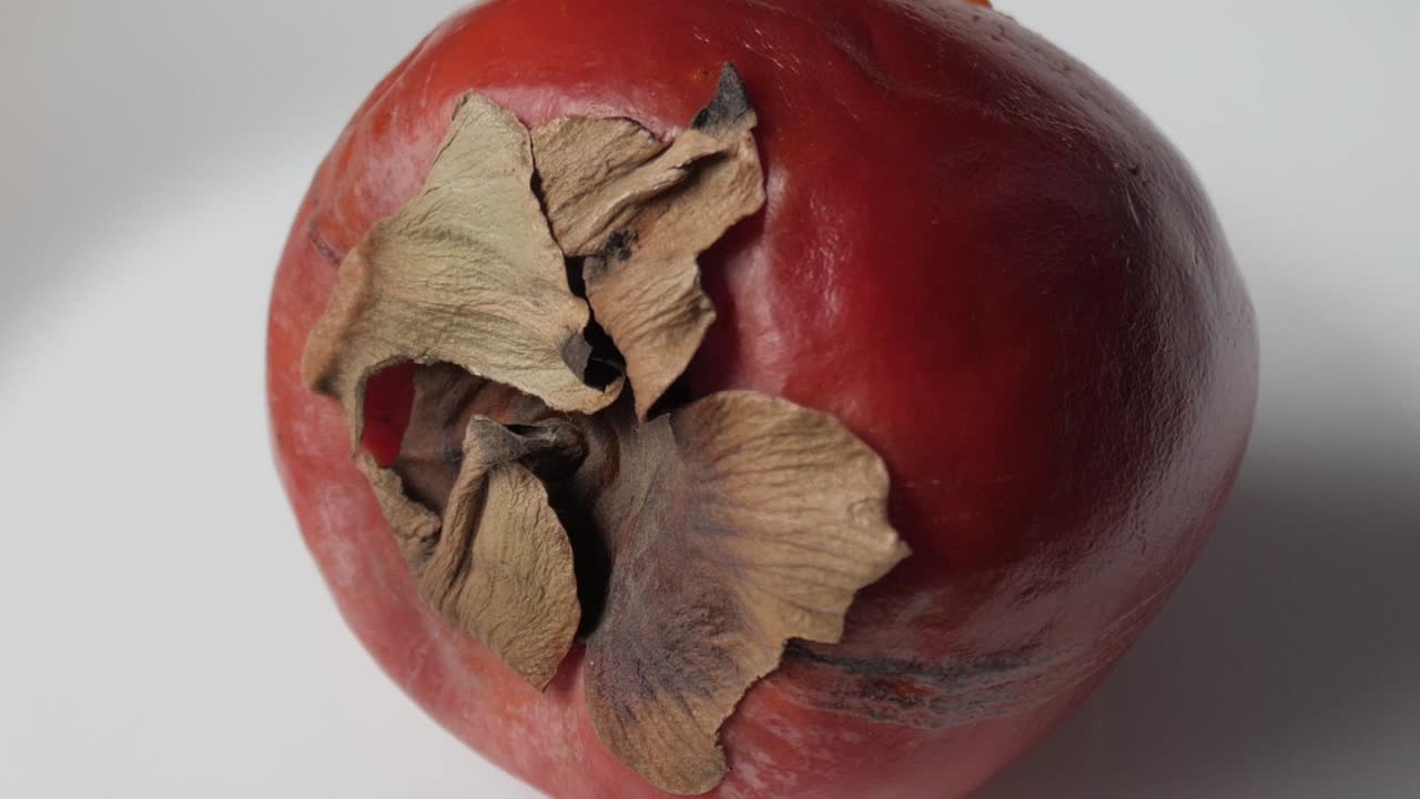 Super nærbillede af en moden persimmon på en hvid tallerken. Panorerende udsigt