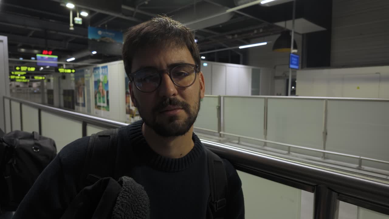 Traveler standing in dimly lit airport terminal with luggage