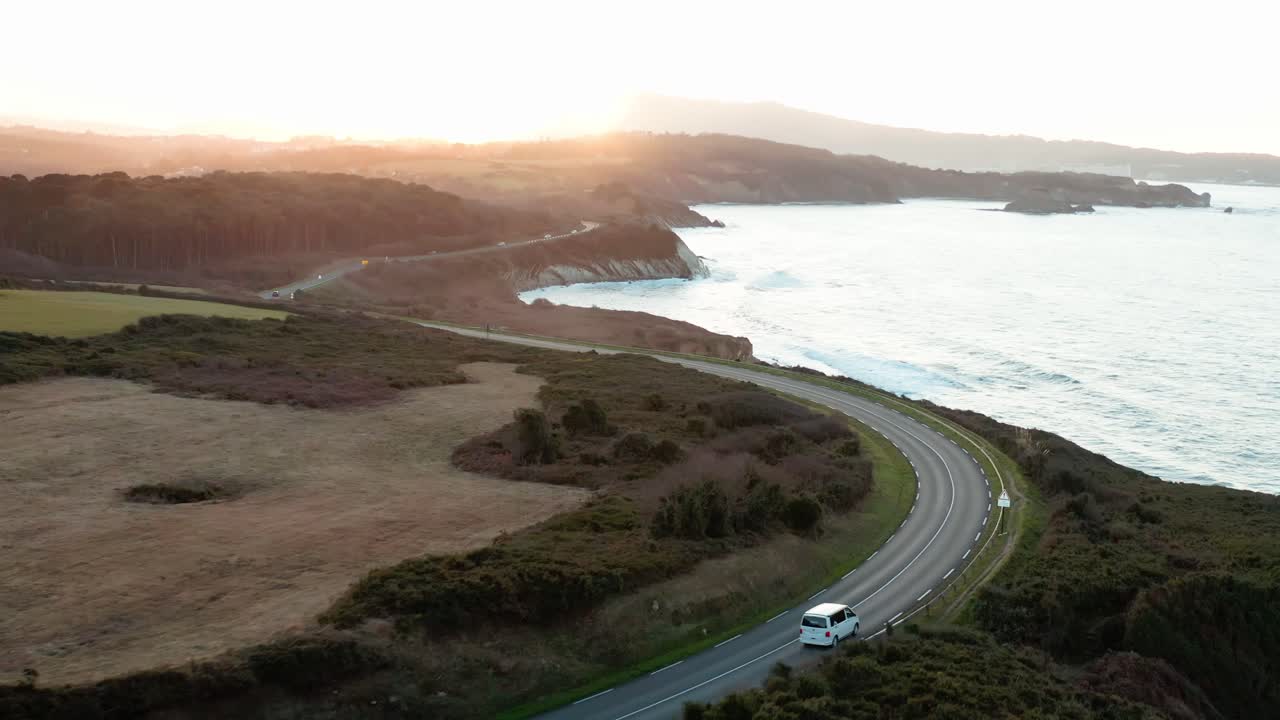 Drone video of a van driving along the ocean with a sunset.