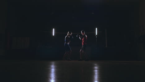 Kickboxer-Mujer-Atleta-Entrenador-De-Kickboxing-Entrenamiento-Femenino-Fitness-Amigos-Boxeo-Puñetazos-Enfoque-Guantes-Disfrutando-De-Intenso-Ejercicio-Juntos-En-El-Gimnasio-De-Cerca