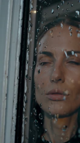 woman looking through a rainy window