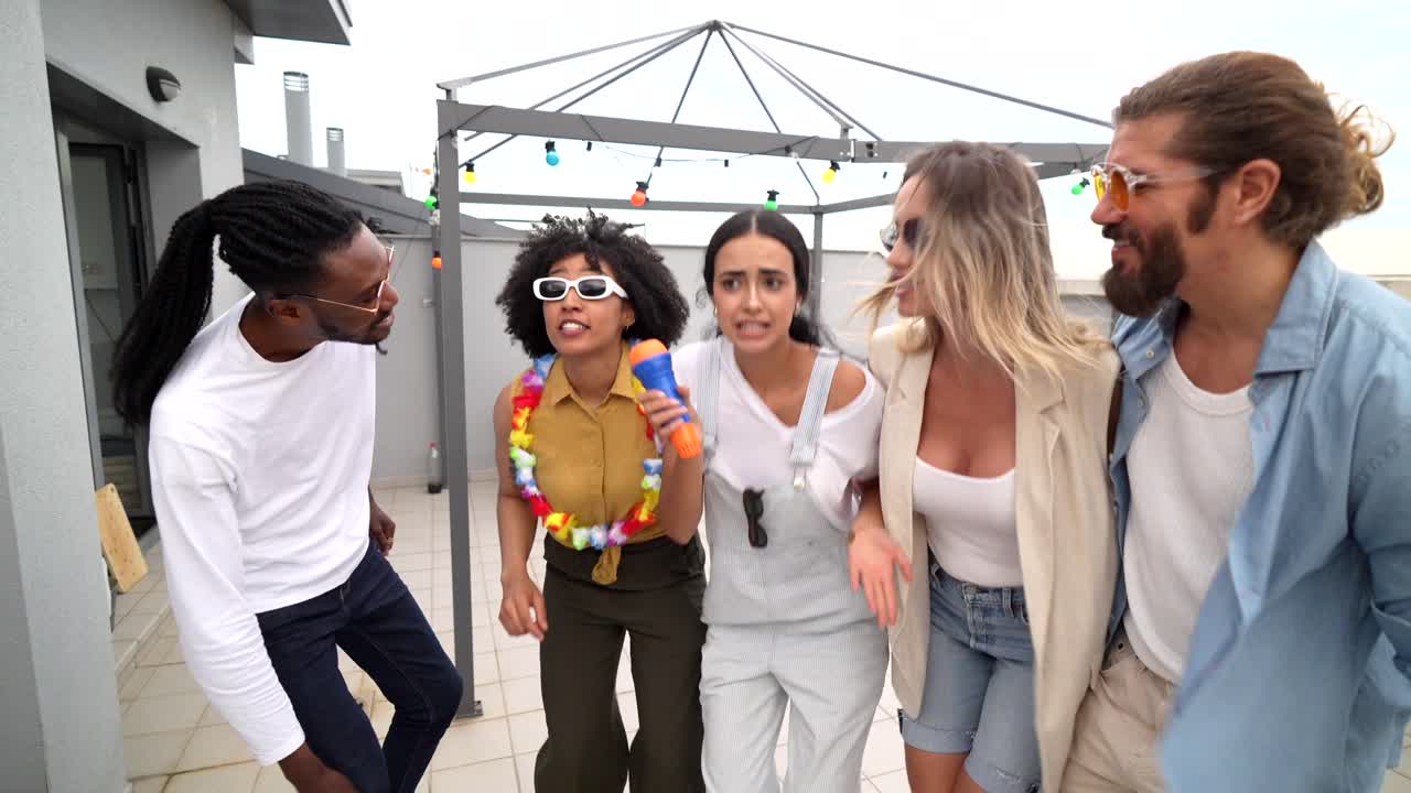 Group of friends having fun singing karaoke on a rooftop party
