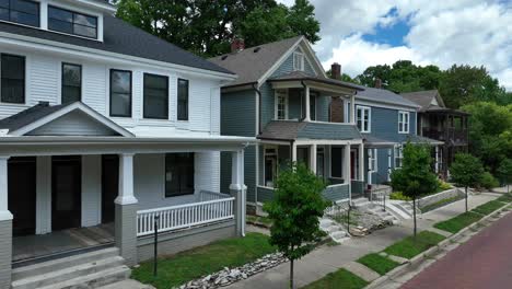 row of traditional american houses with front porches and a cobblestone street