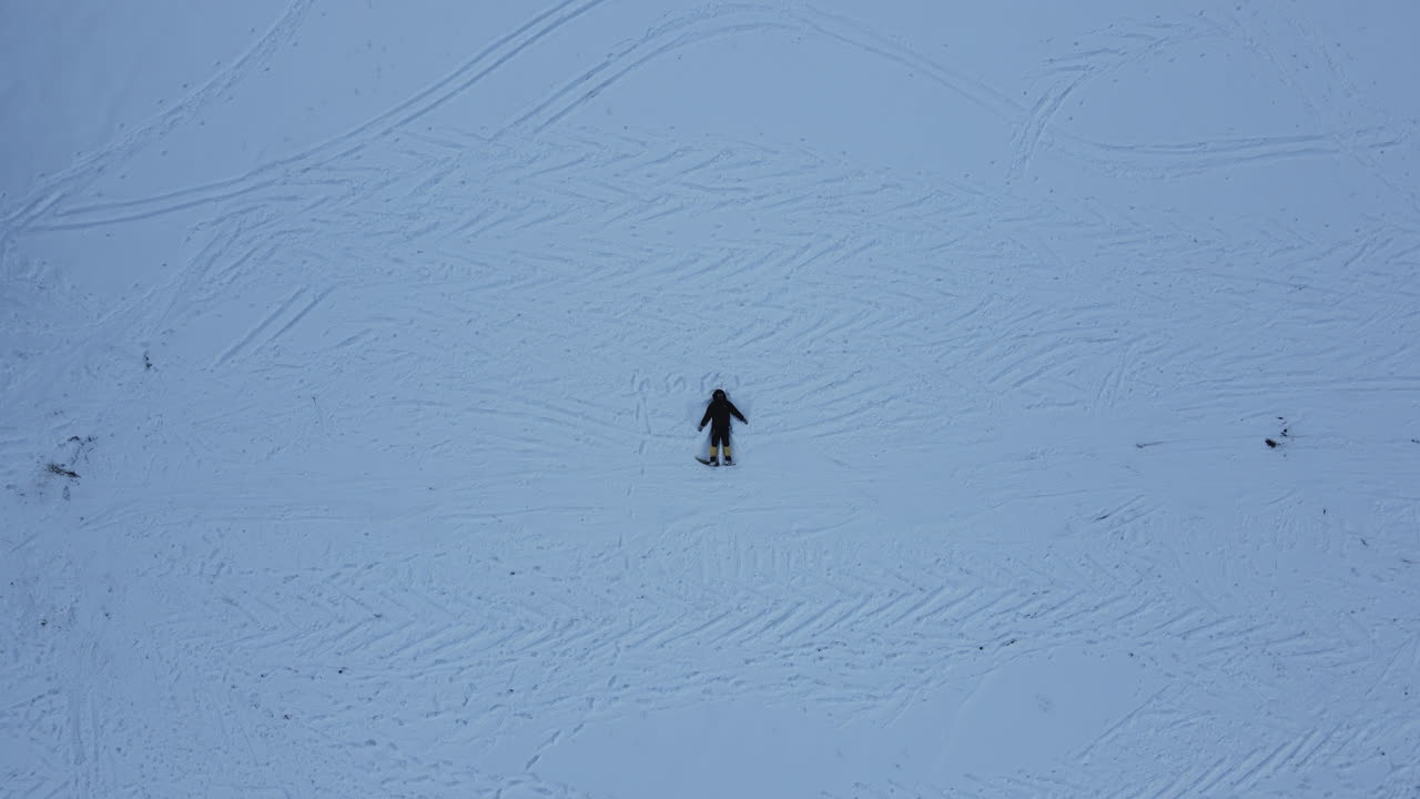 tomada de avión no tripulado de un hombre durmiendo en tierra nevada balanceando manos y piernas para sentir la naturaleza en manang nepal, maravillosa experiencia en el circuito de annapurna 4k