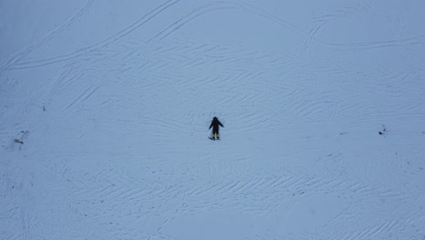 Toma-De-Drone-De-Un-Hombre-Durmiendo-En-Tierra-Nevada-Balanceando-Manos-Y-Piernas-Para-Sentir-La-Naturaleza-En-Manang-Nepal,-Maravillosa-Experiencia-En-El-Circuito-De-Annapurna-4k