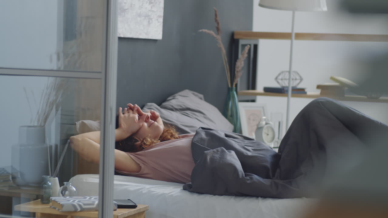 침대에서 휴식을 취하고 전화를 사용하는 여자