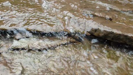 flowing water from a mountain spring water stream running down huge sandstone slabs of rock with green moss, crystal clear drinking water, meditate tranquil and peaceful calm slow motion footage