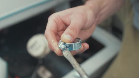 detailed view of male hands demonstrating opening a jubilee clamp