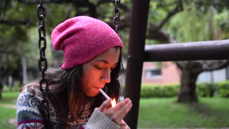 young woman smoking a cigarette in a swing