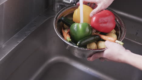 Caucasian-male-chef-washing-vegetables-in-sink-in-kitchen,-slow-motion