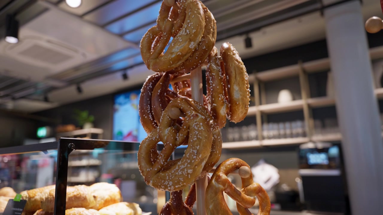 Sugar-coated pretzels hanging on display in a modern bakery or café. Concepts of baked food, snack retail, confectionery and fresh pastry presentation